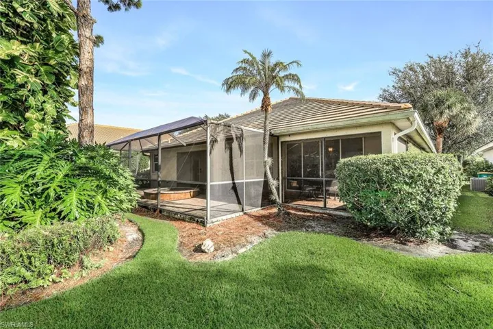 Rear view of house featuring a yard, a sunroom, and central AC unit