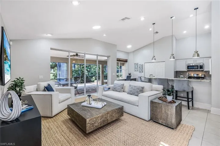 Tiled living room featuring ceiling fan and high vaulted ceiling