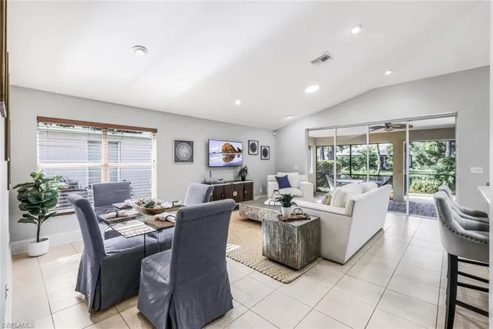Living room with ceiling fan, lofted ceiling, and light tile patterned floors
