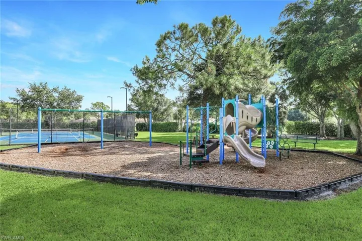 View of play area with tennis court and a yard