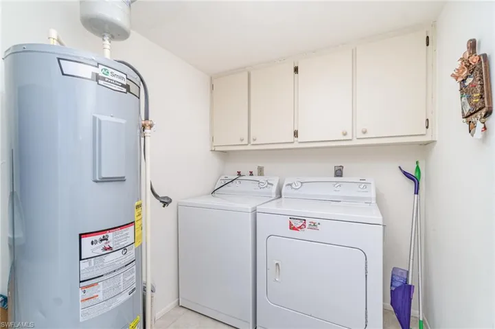 Laundry room featuring water heater, washing machine and dryer & cabinets.