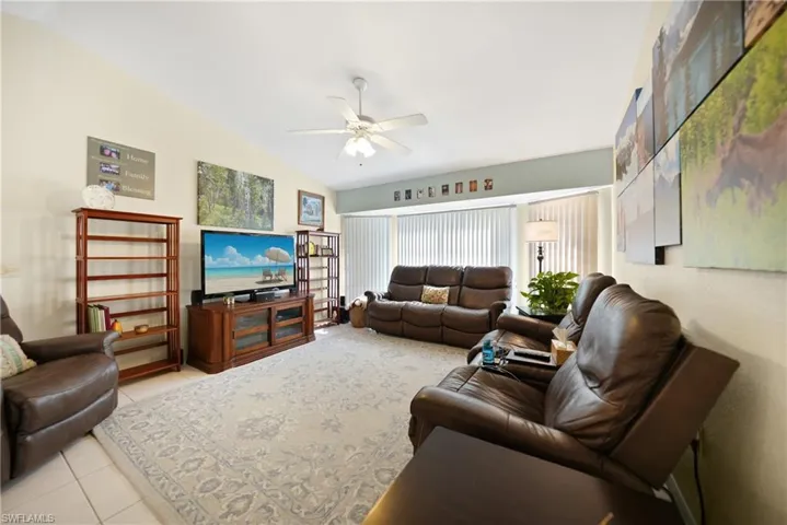 Tiled living room featuring lofted ceiling and ceiling fan