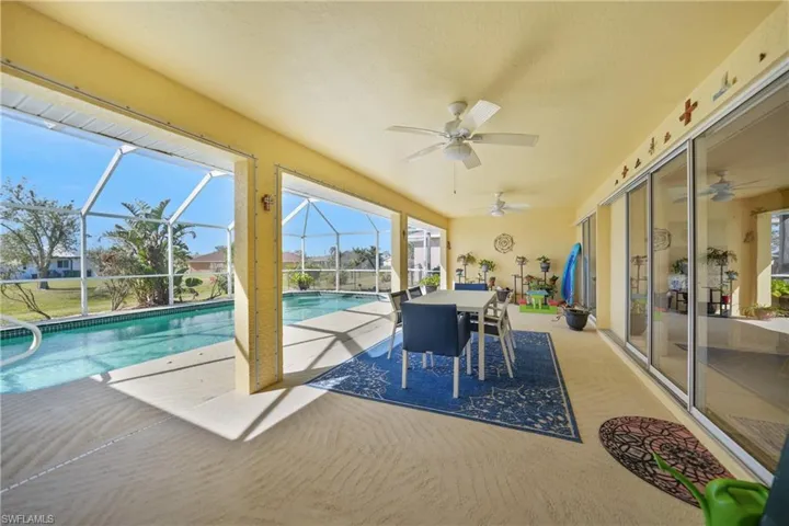 View of pool with ceiling fan, glass enclosure, and a patio area
