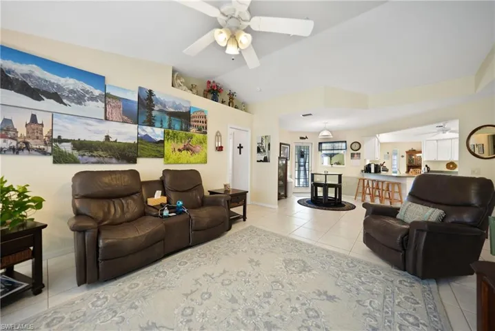 Living room with ceiling fan, lofted ceiling, and light tile patterned floors
