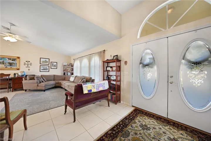 Entryway with lofted ceiling, light tile patterned floors, and ceiling fan