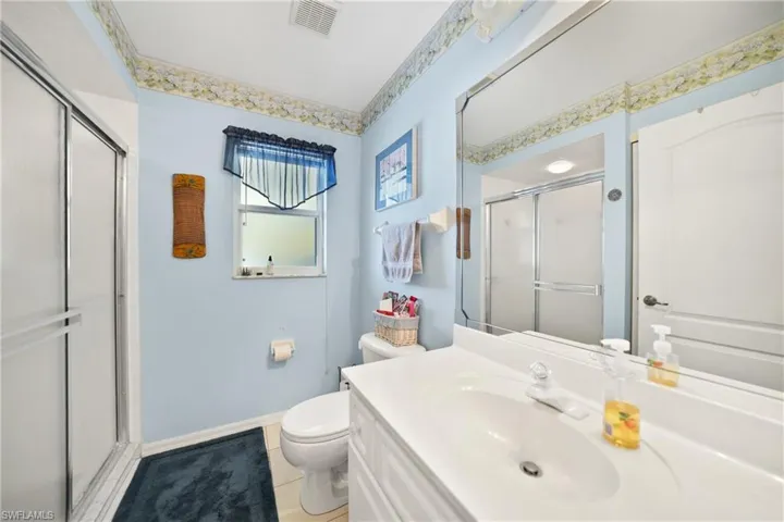 Bathroom featuring vanity, tile patterned flooring, a shower with door, and toilet