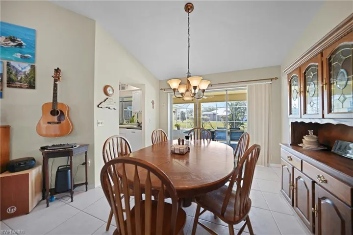 Tiled dining area featuring an inviting chandelier and vaulted ceiling