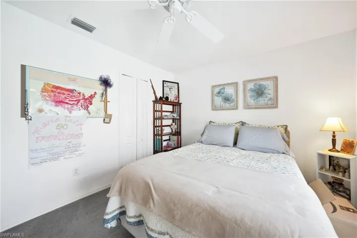 Carpeted bedroom featuring ceiling fan and a closet