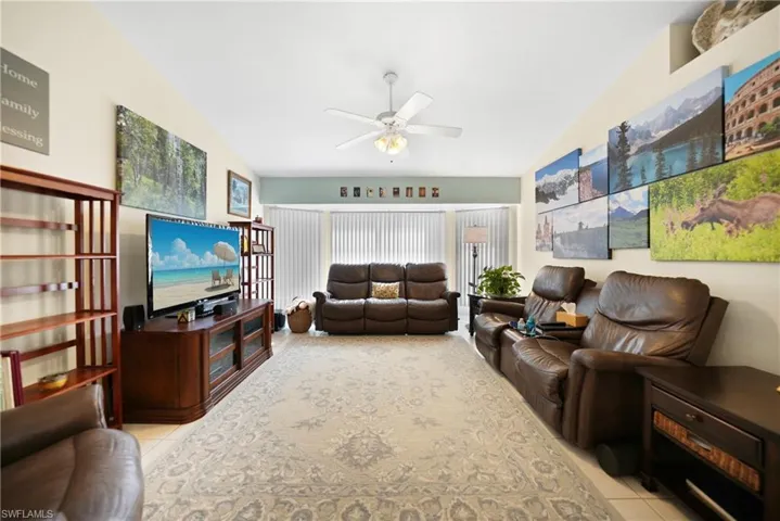 Living room featuring ceiling fan, lofted ceiling, and light tile patterned floors