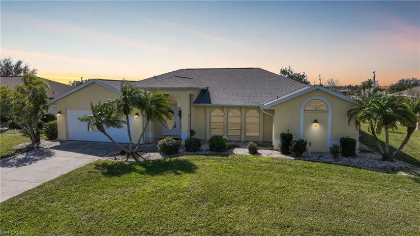 Ranch-style home with a garage and a lawn