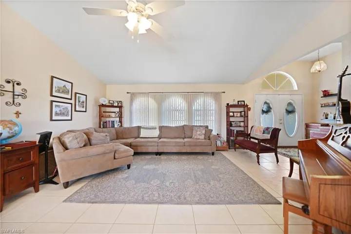 Tiled living room with ceiling fan and vaulted ceiling