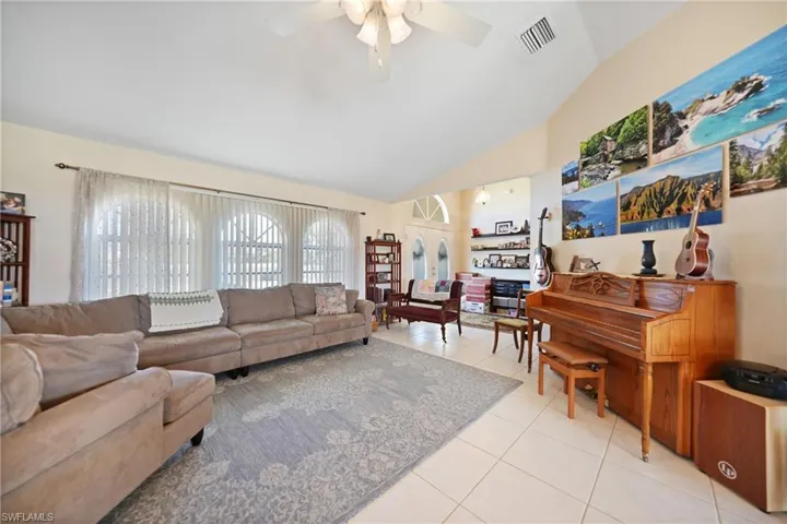 Tiled living room featuring ceiling fan and vaulted ceiling