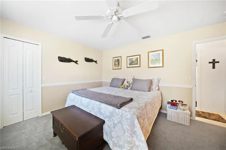 Carpeted bedroom featuring ceiling fan and a closet