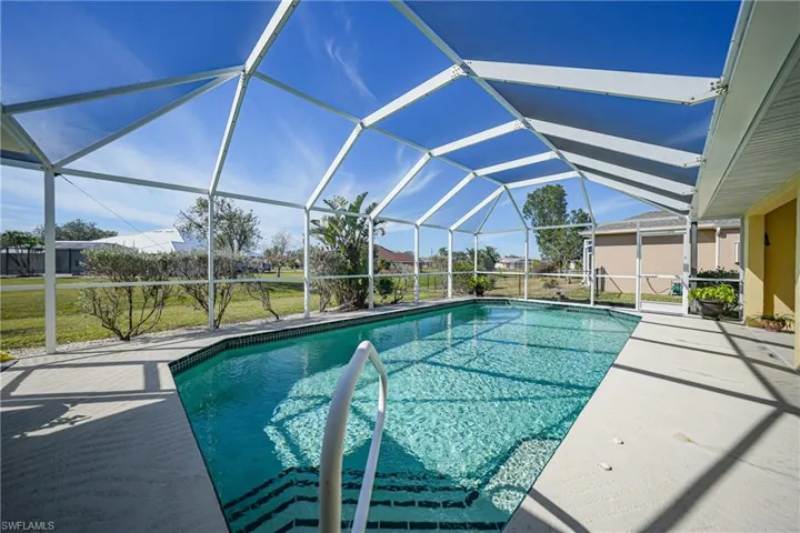 View of pool featuring a patio area and glass enclosure
