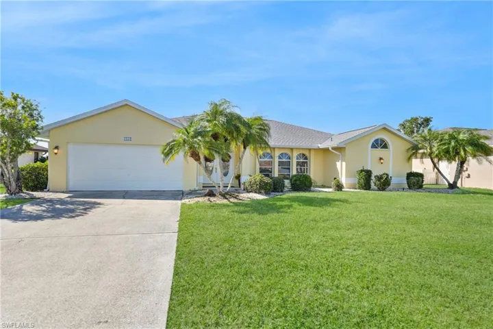 Single story home with a garage and a front lawn