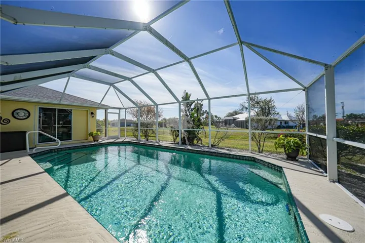 View of pool with glass enclosure and a patio area