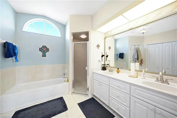Bathroom with tile patterned flooring, plus walk in shower, vaulted ceiling, and vanity