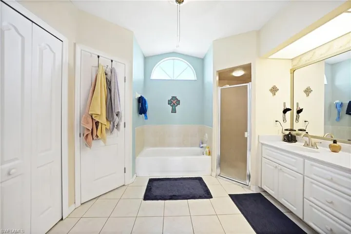 Bathroom featuring shower with separate bathtub, lofted ceiling, tile patterned floors, and vanity