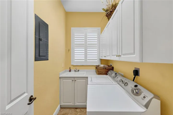 Laundry area featuring electric panel, cabinet space, independent washer and dryer, and light tile patterned floors
