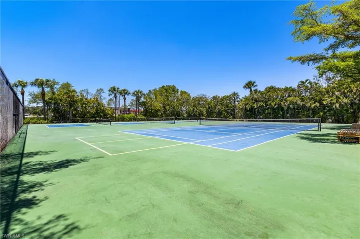 View of tennis court featuring community basketball court and view of scattered trees