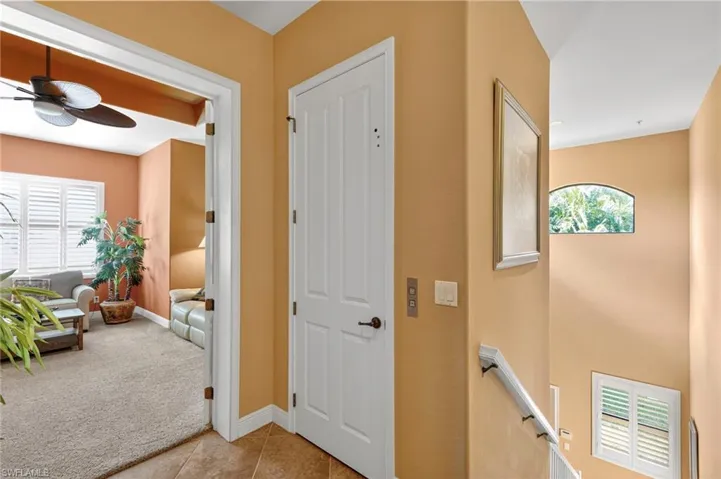Foyer entrance with light carpet, light tile patterned floors, and ceiling fan