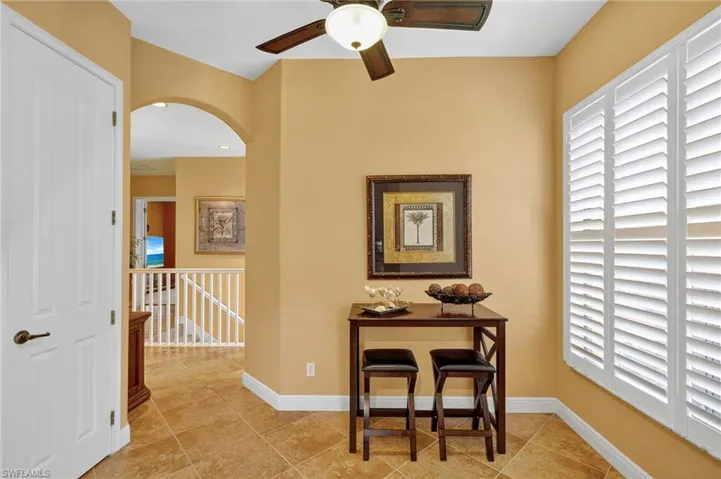 Hall featuring light tile patterned flooring, arched walkways, and an upstairs landing
