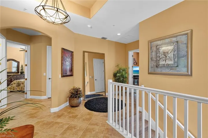 Hall featuring arched walkways, recessed lighting, light tile patterned floors, and a chandelier