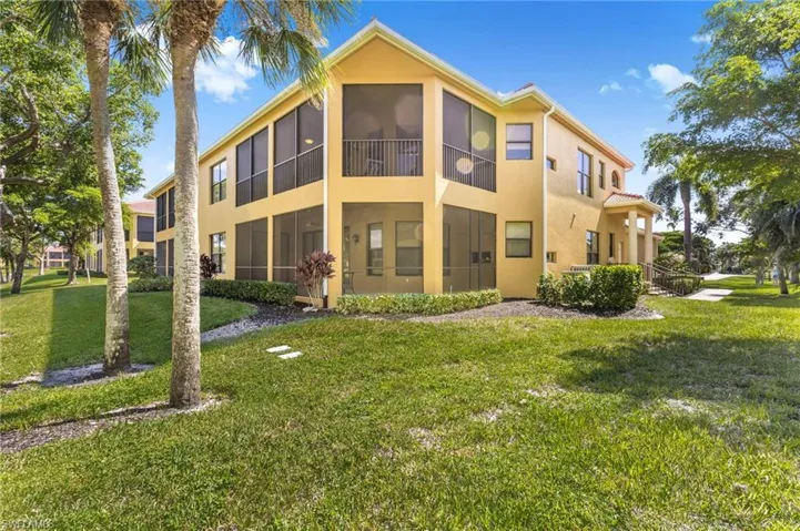 Rear view of property with a sunroom, a yard, stucco siding, and a balcony