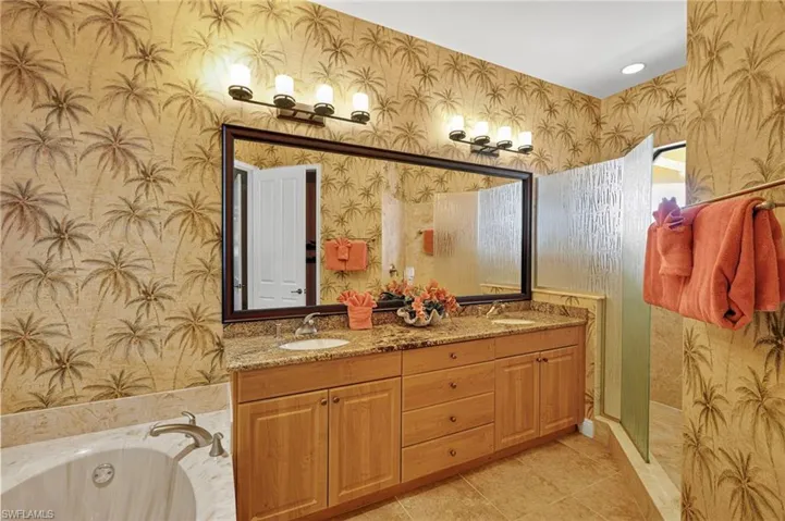 Full bath featuring wallpapered walls, double vanity, a bath, light tile patterned floors, and a shower stall