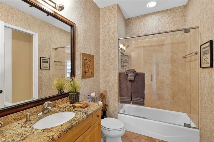 Bathroom featuring vanity, combined bath / shower with glass door, light tile patterned floors, wallpapered walls, and recessed lighting