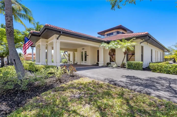 View of front of home with asphalt driveway, stucco siding, a tiled roof, covered porch, and french doors
