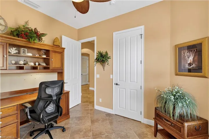 Office area with arched walkways, a ceiling fan, and light tile patterned floors