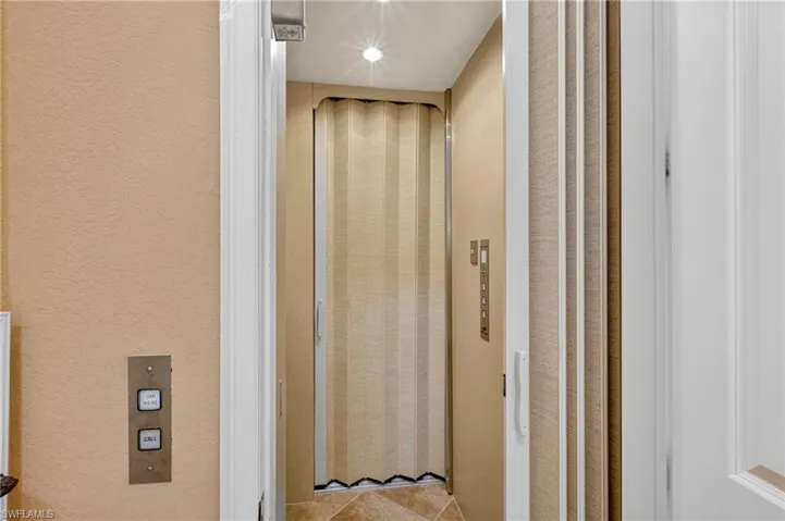 Elevator featuring a textured wall and recessed lighting