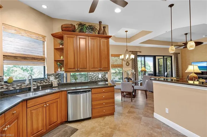 Kitchen with brown cabinets, tasteful backsplash, stainless steel dishwasher, dark stone counters, and recessed lighting