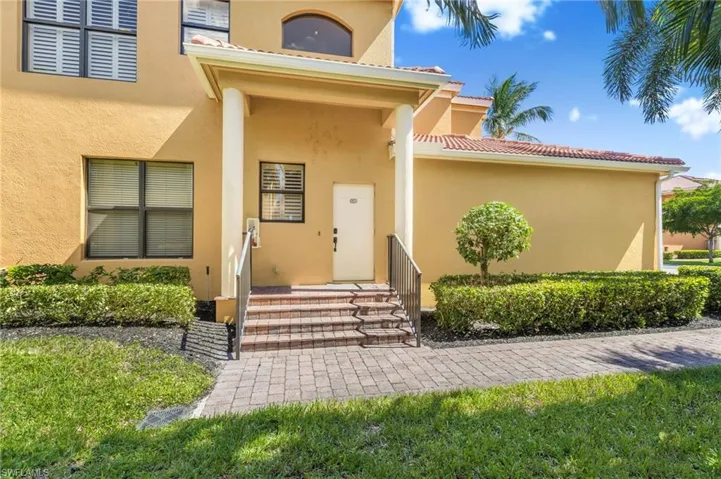 Entrance to property featuring stucco siding, a tiled roof, and a lawn