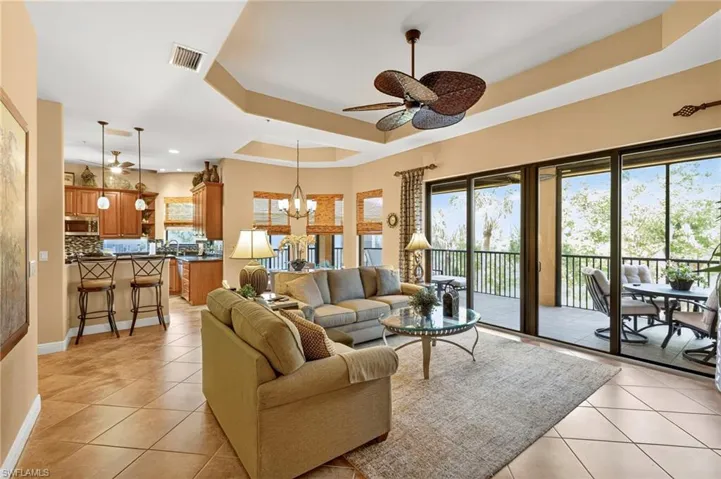 Living room with a raised ceiling, a chandelier, a ceiling fan, and light tile patterned floors
