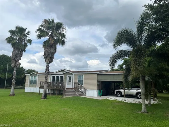 Rear view of house with a carport and a yard