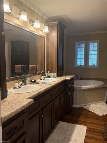 Bathroom featuring a tub to relax in, vanity, hardwood / wood-style flooring, and ornamental molding