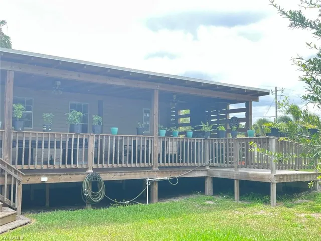 Rear view of house featuring a lawn and a deck