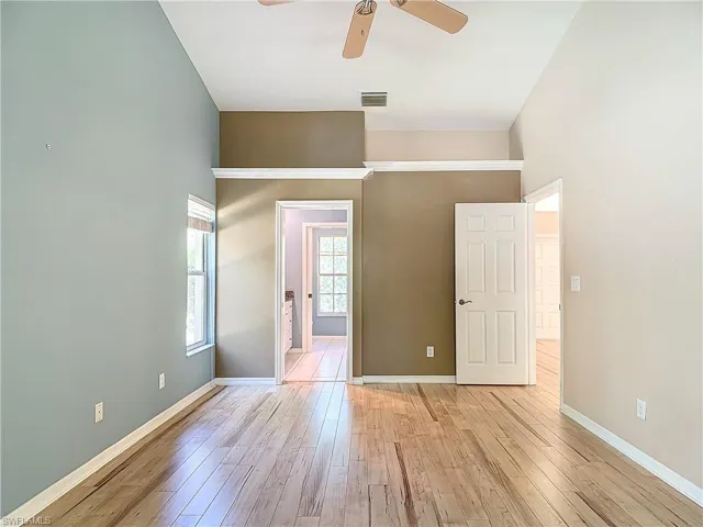 Empty room featuring a towering ceiling, ceiling fan, and light hardwood / wood-style flooring