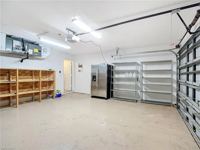Garage with a garage door opener and stainless steel fridge