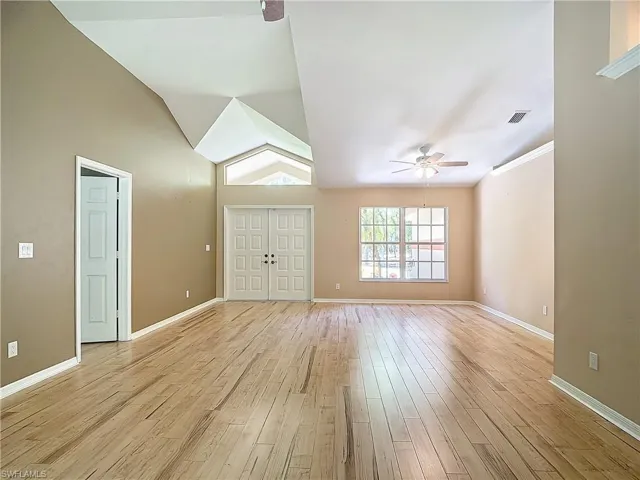 Unfurnished living room with ceiling fan, vaulted ceiling, and light hardwood / wood-style flooring