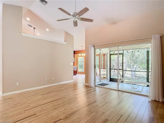 Empty room with high vaulted ceiling, ceiling fan, and light wood-type flooring