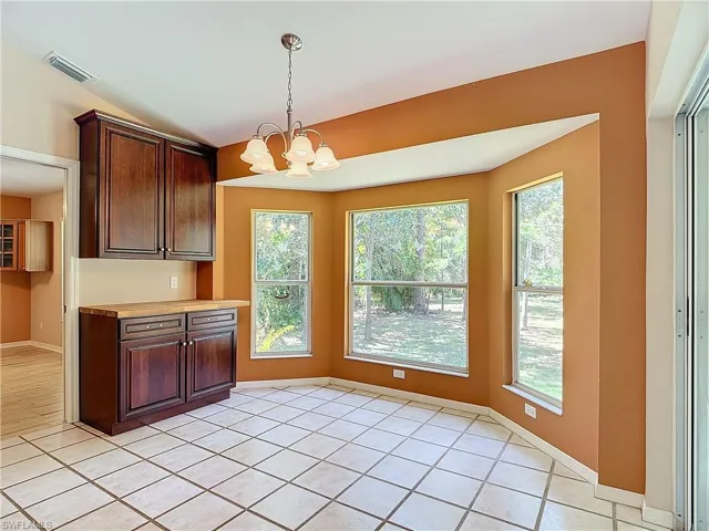 Kitchen featuring a healthy amount of sunlight, hanging light fixtures, light tile floors, and an inviting chandelier