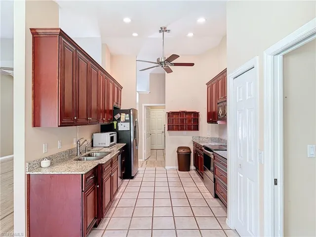 Kitchen featuring sink, light tile flooring, ceiling fan, and stainless steel appliances