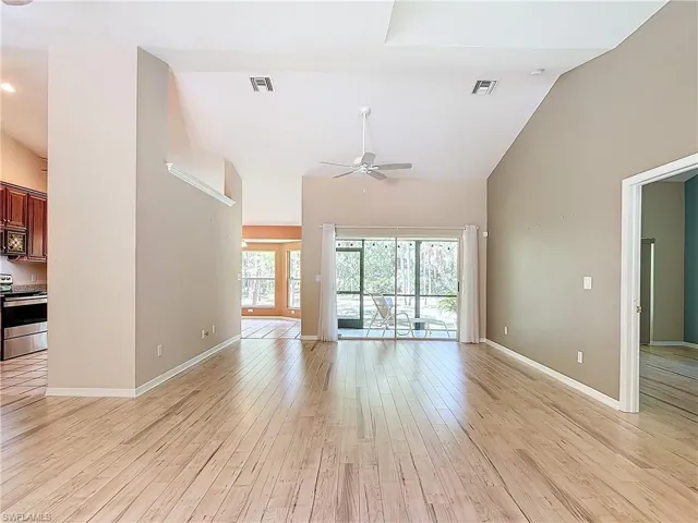 Unfurnished living room featuring high vaulted ceiling, ceiling fan, and light wood-type flooring
