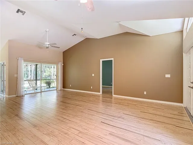 Empty room with high vaulted ceiling, ceiling fan, light hardwood / wood-style flooring, and a skylight