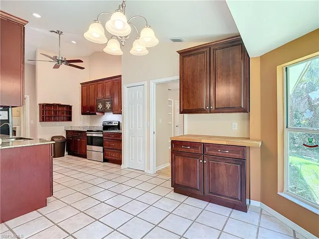Kitchen with a wealth of natural light, built in microwave, light tile floors, and stainless steel electric range oven