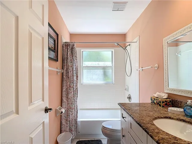 Full bathroom featuring tile flooring, shower / tub combo with curtain, toilet, and vanity