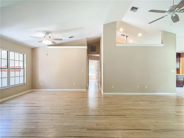 Spare room featuring vaulted ceiling, ceiling fan, and light hardwood / wood-style flooring